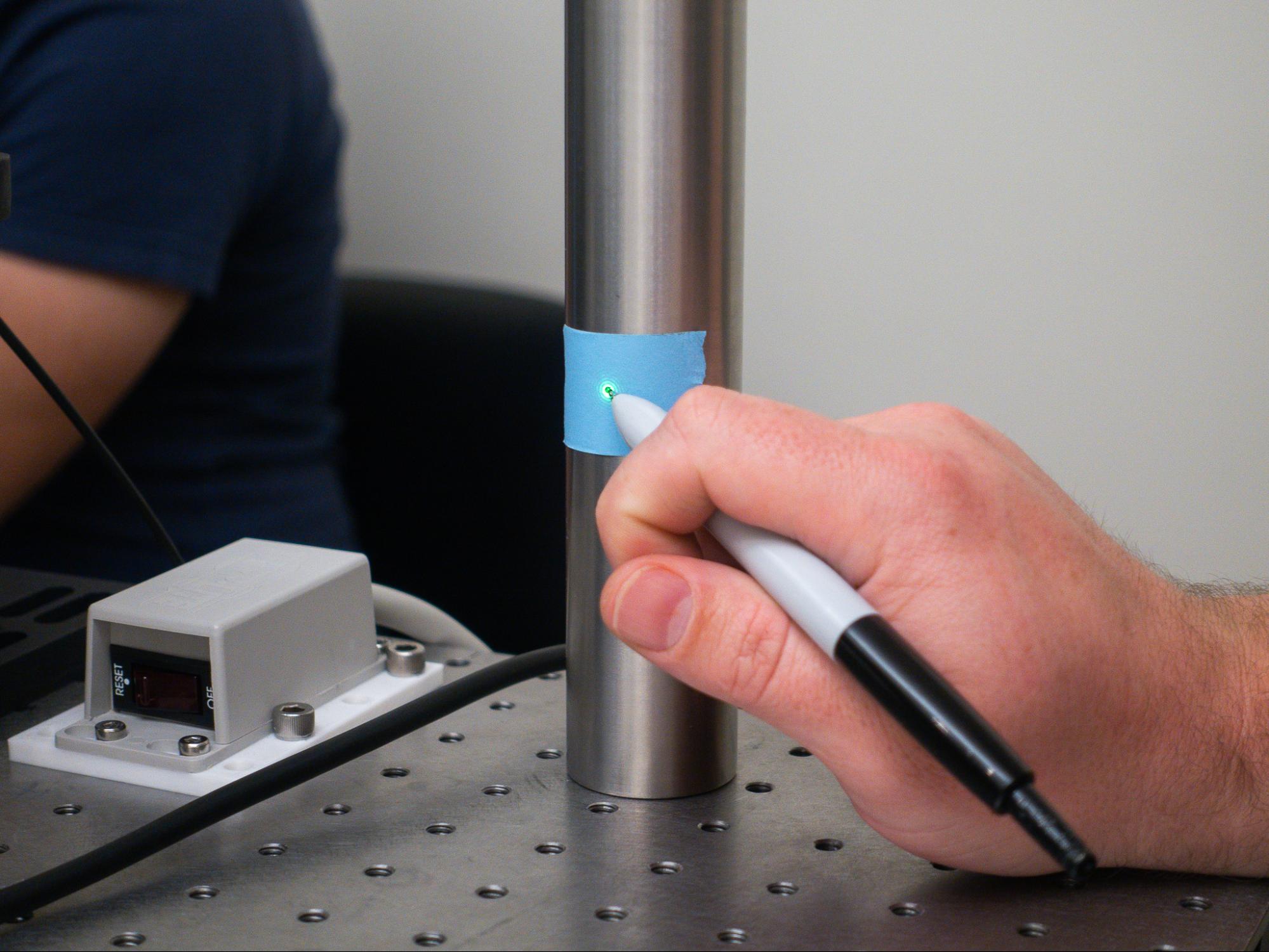 Marking the position of a laser spot on a post, with a pen