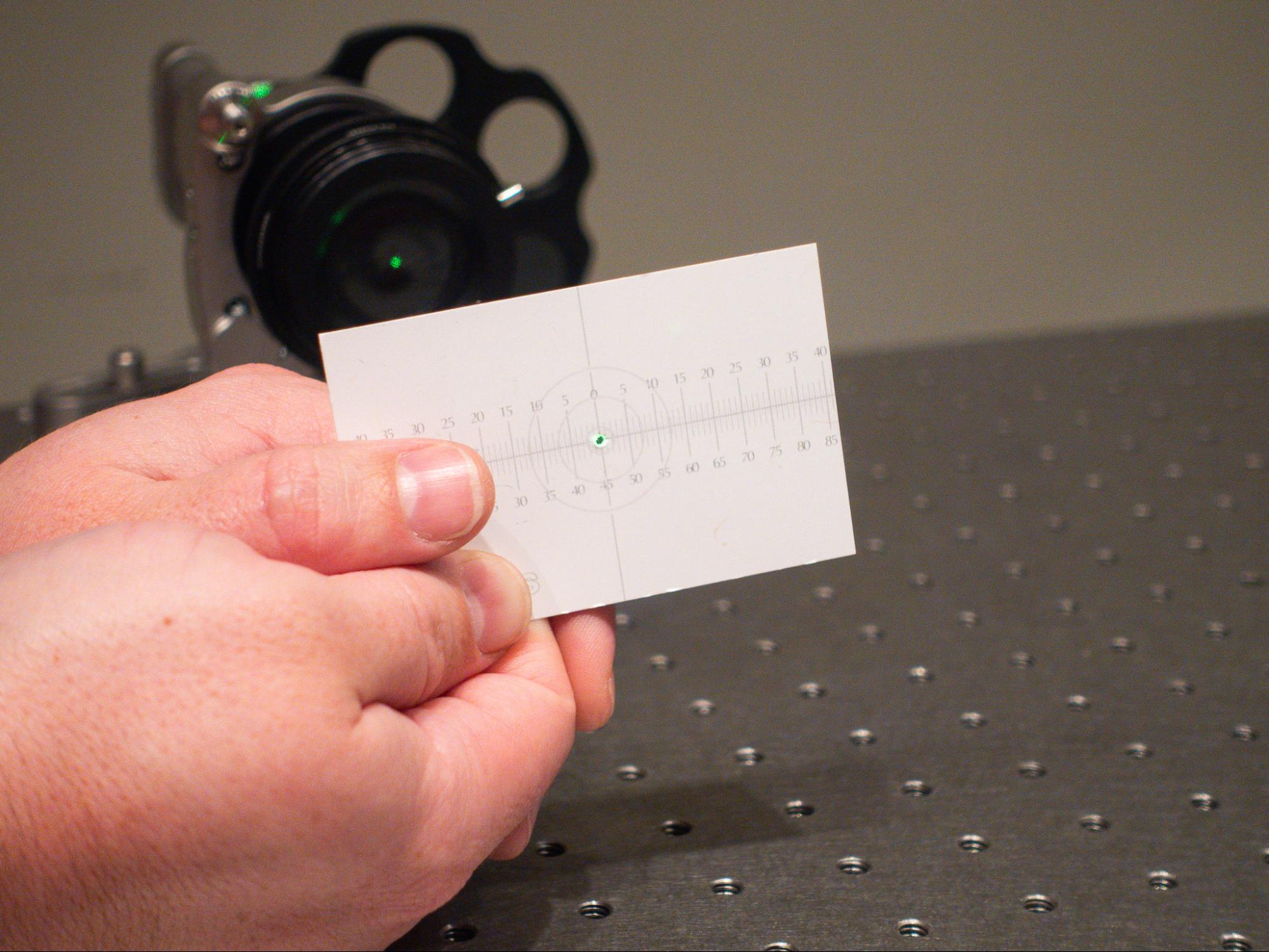 A laser spot passing through a punched hole in a card, showing backreflections.