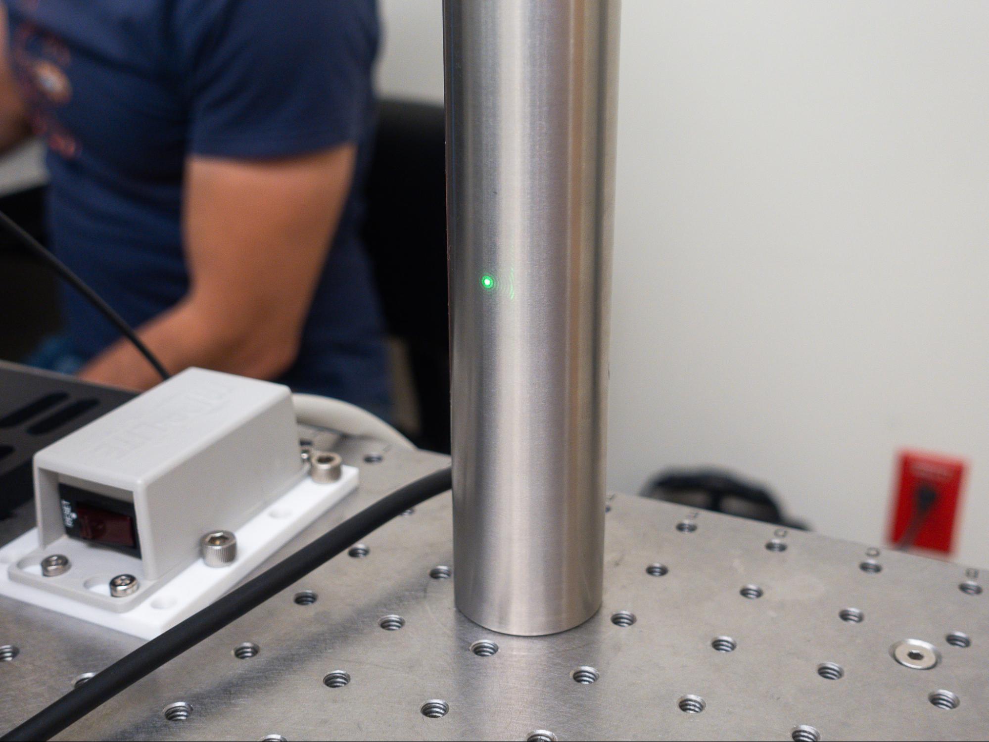 A laser spot on a post with a muscular arm in the background