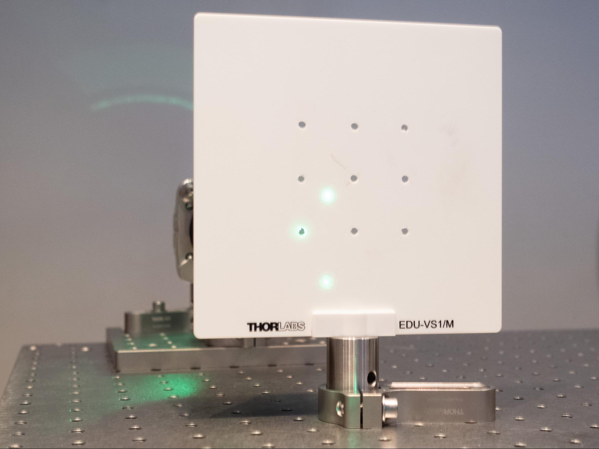 A laser spot passing through a drilled hole in a screen, showing backreflections.